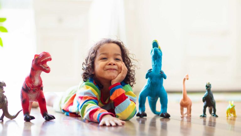 Child calmly lining up toys on the floor, reflecting autism and lining up toys as a pattern of play