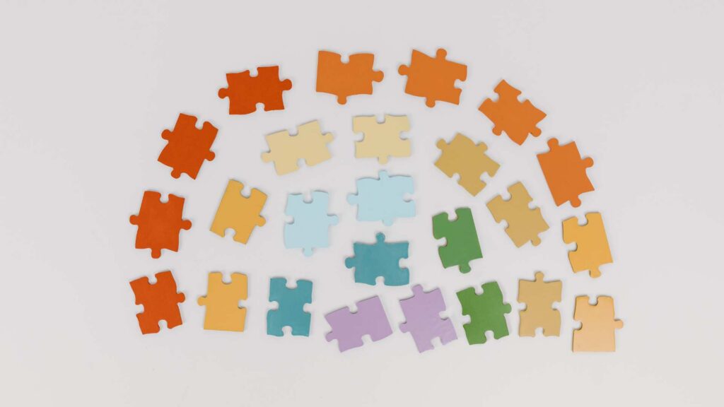 Colorful puzzle pieces arranged like a rainbow, used to talk about celebrities with autism and the importance of autism visibility