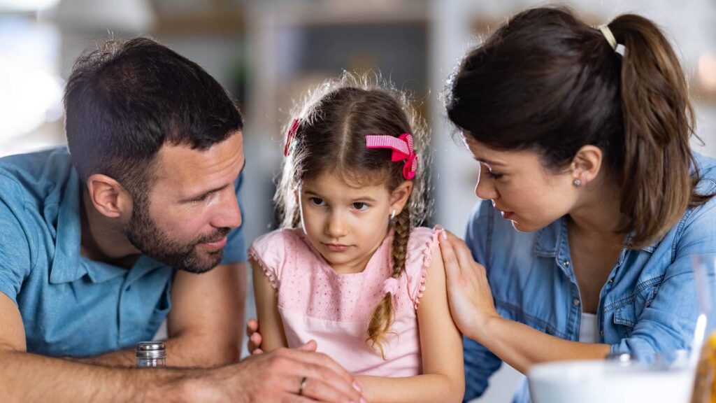 Concerned parents comfort their young daughter at home, capturing the grief after a child's autism diagnosis