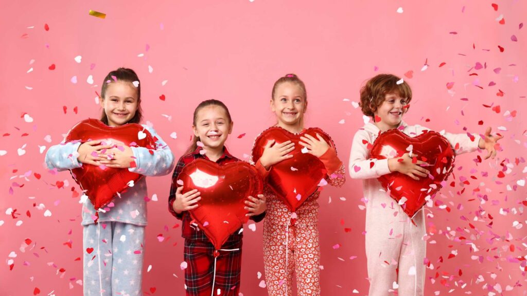 Kids standing together with heart‑shaped balloons and confetti, creating a bright autism and Valentine´s Day scene that highlights love and kindness