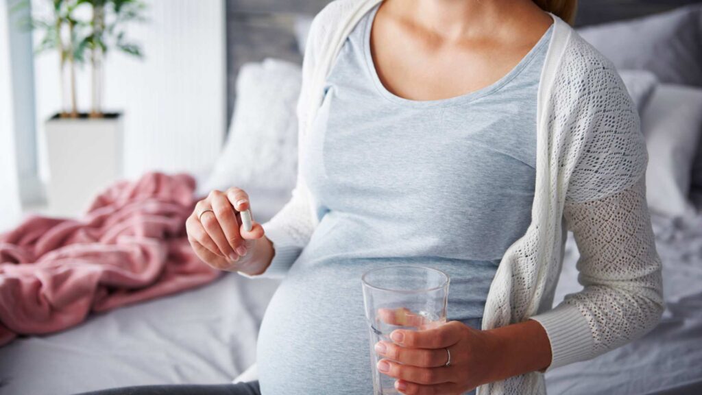 Pregnant woman holding a Tylenol pill