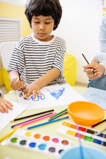 Child using watercolors and colored pencils for a creative drawing session at home.