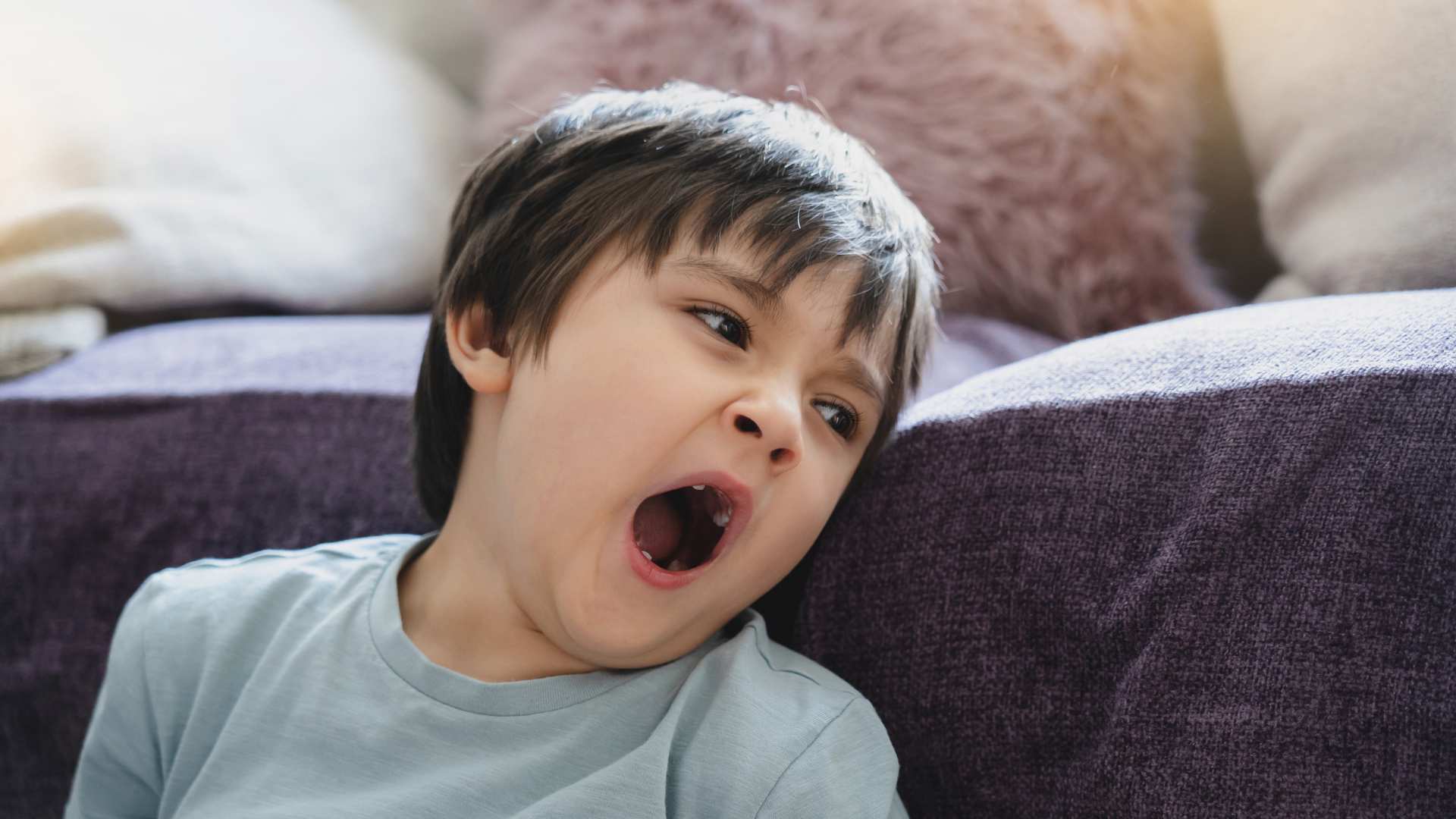 Tired child yawning at home, representing sleep and autism concerns